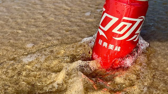 早起看日出海浪一浪接一浪，把可口可乐拍在了沙滩上